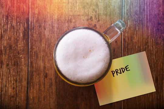Glass of Beer on the Wooden Table at Bar with Rainbow light , Paper Note and Word : Pride, Gay Concept