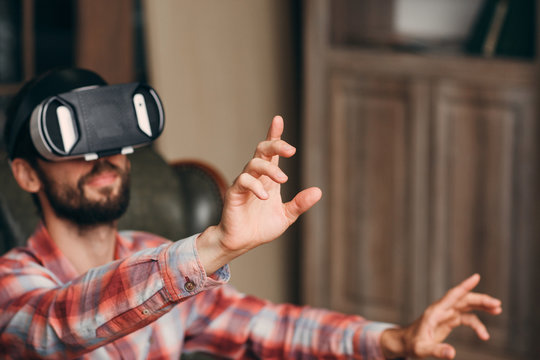 Man in vr goggles touching something, void. Blurred background of male in virtual reality headset. focus on finger pushing invisible icon