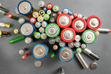 Selection of different batteries, top view on colorful commercial accumulators on gray background....