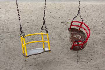 Broken swing hanging on the playground. Danger