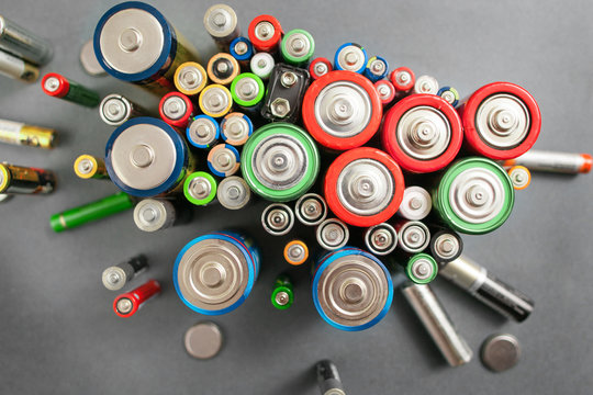 Selection of different batteries, top view on colorful commercial accumulators on gray background. Creative energy composition. Ecology concept