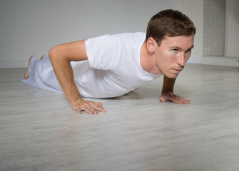 Fototapeta na wymiar Young man doing pushups on the floor.