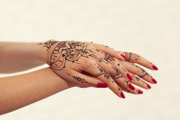 Red manicured hands with Mehndi