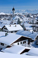 Bavarian Winter Idyll - Traditional houses and church of the town of Nesselwang in front of the bavarian alps, all covered by snow