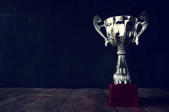 trophy over wooden table and dark background