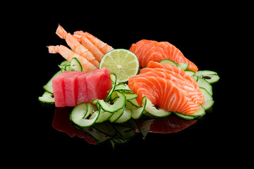 Panele Szklane  Zestaw sashimi (krewetki, łosoś, tuńczyk) z limonką i ogórkiem na czarnym tle.