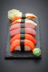 Obrazy na Plexi  Nigiri sushi ustawione na kamiennej płycie na czarnym tle