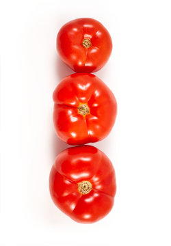 A tomato. Red tomato on a white background. Harvest vegetables. Autumn harvest. Red, juicy, ripe tomato.