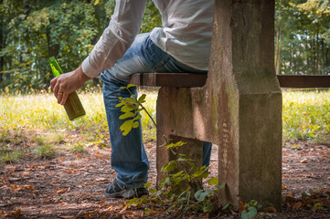 Obraz premium Man depressed with beer bottle sitting on a park bench