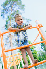 Smiling kid having fun at playground. Child doing gymnastic exercises
