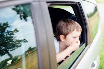 Child suffers from motion sickness in car - obrazy, fototapety, plakaty