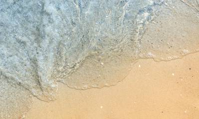 Fototapeta na wymiar wave of blue sea on sandy beach. Top view