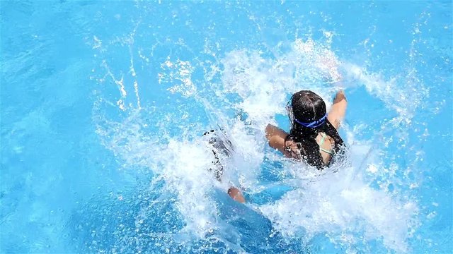 Two little girls in swimsuit jumping in pool, slow motion
