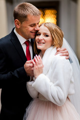 Handsome groom is hugging his beautiful bride