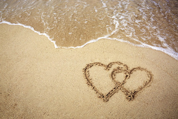 Two hearts drawn on the sand of a beach.
