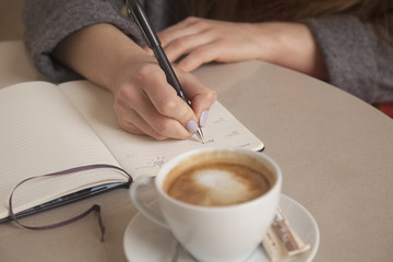 Close-up of female hands. Woman writing plan in notepad. Signing