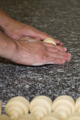 Baker making croissants on grey background