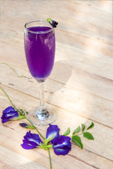 Butterfly pea juice in glass on wooden table with flower.