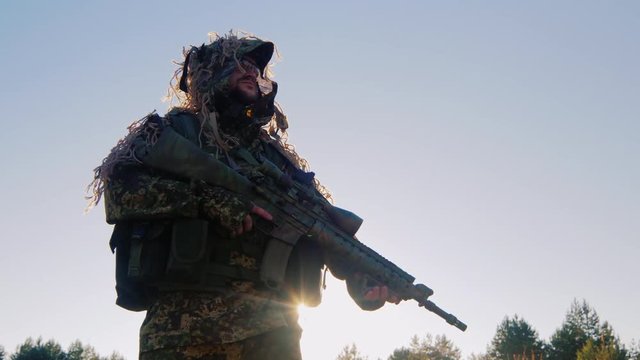Armed man in military uniform. It should be against the sky, the sun is shining from behind his armor