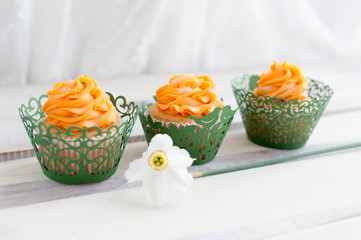 Three cupcakes with orange cream and flower