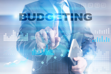 Businessman is pressing button on touch screen interface and selecting "Budgeting".