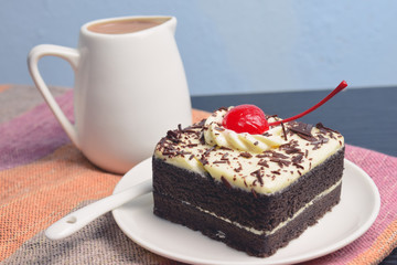 Chocolate cake with cherry and milk jug on plate  mat