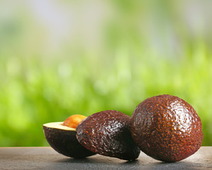 Fresh avocados on gray table. Blurred green background.