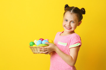 Cute girl with Easter eggs on yellow background