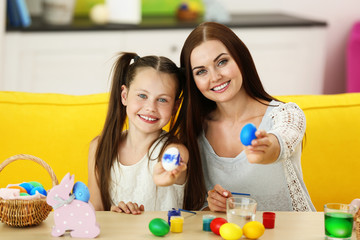 Mother and daughter painting eggs at Easter eve