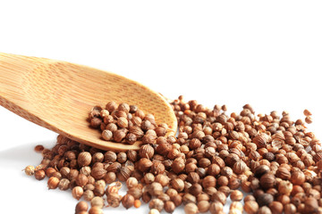 Coriander seeds and wooden spoon on white background