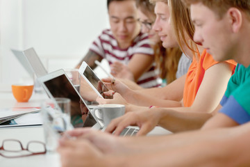 Young people with gadgets sitting at table