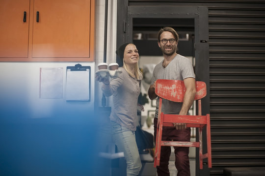 Man and woman with coffee to go and chair leaving workshop