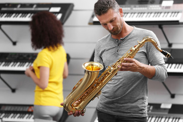 Handsome man playing saxophone in music shop