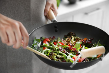 Female hand mixing vegetables in pan closeup