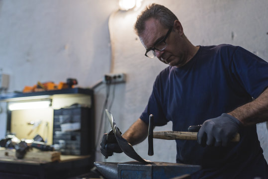Forger hammering metal in workshop