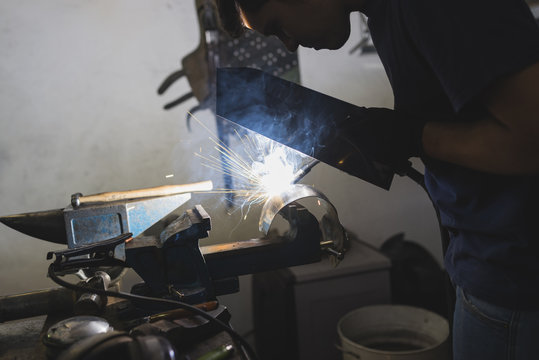 Forger welding metal in workshop