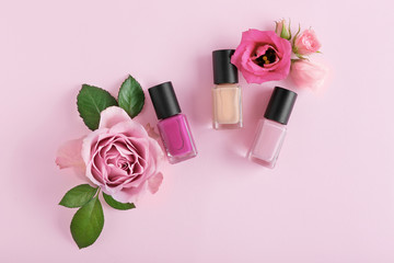Obraz na płótnie Canvas Nail polishes and flowers on pink background