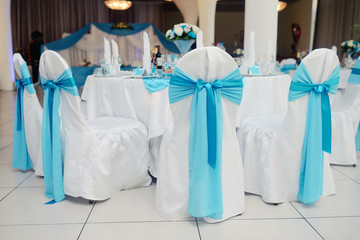 Beautiful fabric bow on the chair. Wedding restaurant for marriage. White decor for bride and groom. Colorful decoration for celebration. Beauty bridal interior