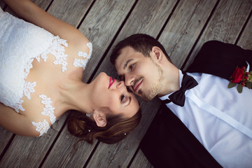 Beautiful bride and groom enjoy a sunny day while lying down on