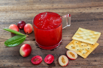 Carandas-plum  juice  in a glass on wooden background  