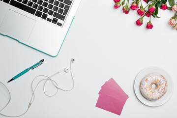 Office desk table with computer, supplies, flowers