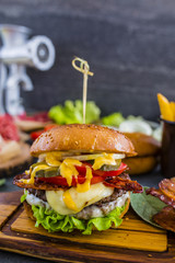 Tasty street food grilled beef burger in crispy shortbread with lettuce and mayonnaise served with french fries on small cutting board.
