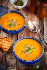 homemade autumn butternut squash soup with pumpkin seeds, bacon and basil