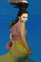 Fototapeta na wymiar Young beautiful woman with long hair in a bright dress under water, underwater fashion in the pool, Odessa, Ukraine