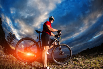 Naklejka premium mountain bicycle rider on the hill with sunrise background