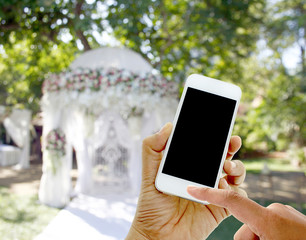 hand hold and touch screen smart phone on wedding tent blurred b