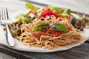 Whole wheat spaghetti topped with organic homemade marinara sauce served with green beans and an Italian side salad macro shot