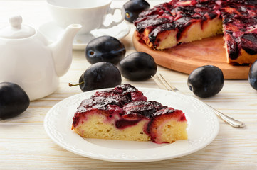 Plum biscuit cake on white wooden background.