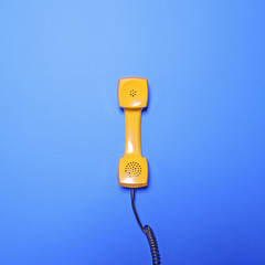 Retro yellow telephone tube on blue background - Flat lay