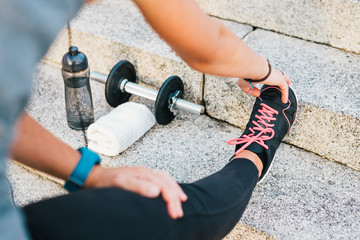 Sport athlete runner female stretching leg on urban stone stairs during training exercise workout...